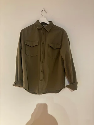 Olivgrön overshirt från Dobber/MQ - Är en olivgrön overshirt från Dobber i storlek S. Overshirt passform är bra. Säljer denna för att jag köpte en annan overshirt.