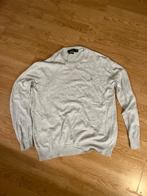 Polo Ralph Lauren tröja - Snygg ljusgrå tröja från Polo Ralph Lauren i slim fit med rund hals och broderad logga på bröstet. Tillverkad i mjuk pima bomull som känns skön mot huden. Perfekt för dig som gillar stilrena och klassiska plagg.