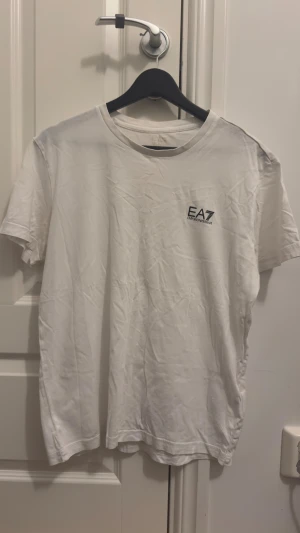 Vit EA7 Emporio Armani t-shirt - En vit enkel Armani T-shirt. Har använts några gånger men väldigt sparsamt. Inga fläckar eller något liknanden! Vill du ha flera bilder eller undrar du över något, hojta bara till!☺️