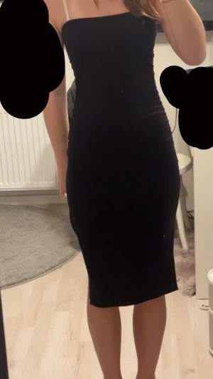 Svart tight klänning med slits - En svart, tight tub klänning. Klänningen är midilång och har en snygg slits på sidan. Enkel och stilren modell som sitter figurnära och framhäver siluetten.