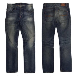Nudie Jeans (Grim tim) - Snygga Nudie Grim Tim i äkta vintage denim med perfekt patina och naturligt slitage. Slim/straight passform som sitter grymt och en tvätt som bara Nudie får till. Bra vintage-skick och redo för ett nytt hem! Storlek- 30/32