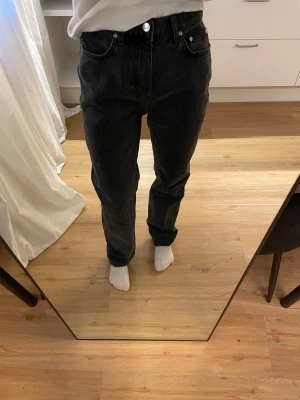 Svarta jeans från A-Dsgn, straight fit - Säljer ett par offblack jeans från A-Dsgn med klassisk femficksdesign och raka ben. Jeansen har hög midja, silverfärgade knappar och bälteshällor. Innerbenslängd ca 77cm. 