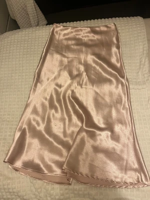 Champagnefärgad satinkjol - Säljer en lång, glansig satinkjol i en snygg champagnefärg. Kjolen har en rak och enkel passform som faller snyggt längs kroppen. Använt endast ett par gånger. 