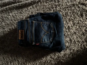 Levi's 511 mörkblå jeans bootcut - Snygga mörkblå Levi's 511 jeans med klassiska kontrastsömmar och femficksdesign. Jeansen har en relativt rak men endå utsvängd passform , perfekt för en stilren look. Tillverkade i slitstarkt denim med Levi's läderpatch bak vid fickan.