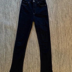 Mörkblå skinny jeans med hög midja - Snygga mörkblå jeans med skinny fit och hög midja. Klassisk femficksmodell med silverfärgad knapp och dragkedja. Jeansen har raka sömmar och är tillverkade i stretchigt denim för en bekväm passform.