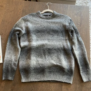 Grå stickad tröja - Lager 157 - Grå stickad tröja från 157 i storlek S. Tröjan har en rundad, ribbad hals och ribbade muddar vid ärmslut och nederkant..
