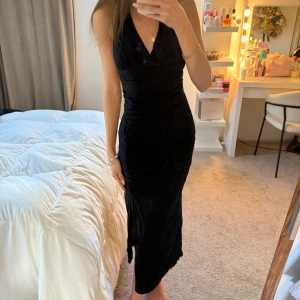 Svart långklänning med v-ringning från Zara  - Säljer en elegant svart långklänning med djup v-ringning och öppen rygg från Zara. Klänningen har en figurnära passform och är ärmlös, har även slits vid ena benet. Aldrig använd 