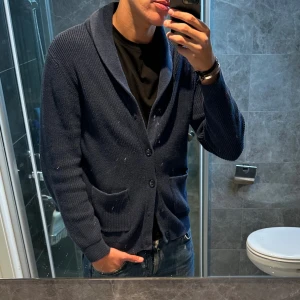 Mörkblå stickad cardigan Mango  - Riktigt snygg mörkblå cardigan från Mango som passar perfekt till både höst och vinter. Tröjan är i riktigt bra skick och har inga skador. Jag är 188cm och bär storlek L. Den är ganska liten för att vara en L så den passar även dig som har M. Hör av er vid funderingar;)
