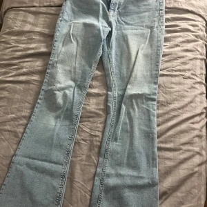 Ljusblå bootcut jeans - Snygga ljusblå jeans med bootcut passform och klassisk femficksdesign. Jeansen har en lätt tvättad look och raka ben som blir vidare nedtill. Perfekta för dig som gillar retrovibbar och vill ha ett par jeans som sticker ut lite extra.