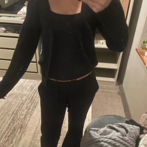 Svart stickad kofta med hålmönster - Säljer en svart stickad kofta med snyggt hålmönster. Koftan är öppen framtill och har lång ärm. Perfekt att slänga över ett linne eller t-shirt för en chill look. Passar både till jeans och kjol.