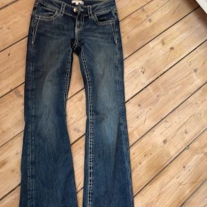 Mörkblå jeans med broderade bakfickor - Snygga mörkblå jeans från Gina Tricot med kontrastsömmar och broderade bakfickor med glittriga detaljer. Klassisk femficksmodell i bootcut med låg midja. Perfekta för dig som gillar jeans med lite extra attityd.