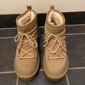 Beige boots  - Snygga beige boots med mjukt foder och snörning framtill. Skorna har en platt och mjuk sula och är perfekta för kalla vinterdagar! Insidan är fodrad med fluffigt material för extra värme och komfort. Dom är i nyskick utom att sulan är lite lite nedtrampad längst ner! Strl 39 men har passat mig som har strl 40! Jag tror att dom är köpt från din sko! Säljer pga att dom inte kom till användning förra vintern och jag tycker att dom är för höga för min smak!💕 nypris ca 850kr! Priset kan diskuteras!🥰