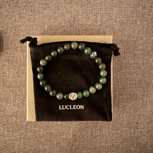 Grönt pärlarmband  - Stilrent armband med runda gröna pärlor och en silverfärgad detalj med ingraverad logga. Kommer i originalpåse och ask, perfekt accessoar för att lyfta din look.