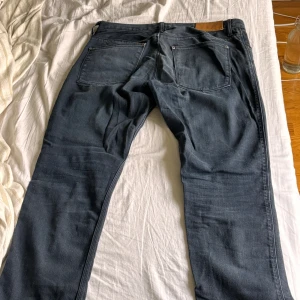 Mörkblå jeans från Acne Studios 33/32 - Snygga mörkblå jeans från Acne Studios med klassisk femficksdesign och raka ben. Jeansen har en stilren look med Acne-logga på läderpatchen bak och metallknappar med logotyp. Tillverkade i slitstarkt bomullsjeansmaterial.