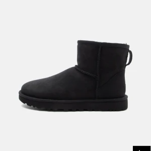 UGG Classic Mini svarta boots - UGG Classic Mini II stövlar i helsvart mocka med rund tå och platt sula. Skorna är fodrade och perfekta för kalla dagar. Klassisk och enkel design som passar till allt, med låg skaftlängd och mjukt material. De har använts en hel del, så de är något fläckade.
