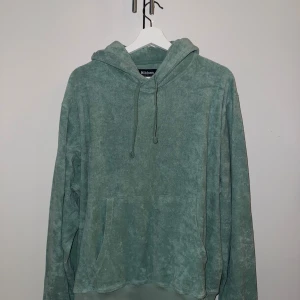 Grön frottéhoodie från Nikben - Mysig grön hoodie från Nikben i frotté med huva och snörning. Tröjan har en stor magficka och avslappnad passform, perfekt för chill dagar. Materialet är mjukt och ger en unik look.