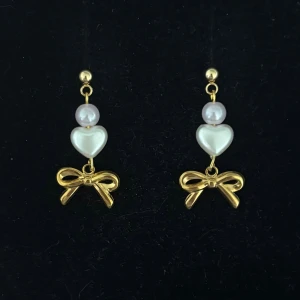 Guldiga örhängen med pärlor och rosett - Handgjorda och unika guldörhängen 🤩 Öronhängerna är nickelfria och guldpläterade i kirurgiskt stål, resterande av örhänget är i rostfritt stål (ej guldpläterat) 💕🙏 3 cm långa. Alla köp görs via ”KÖP NU” knappen.  💐