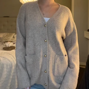 Beige kofta med guldknappar - Mysig beige kofta med v-ringning och stora guldknappar framtill från Zara. Knappt använd och i jättebra skick!