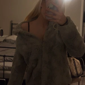 Grå teddyjacka från Vero Moda XS - Mysig grå teddyjacka från Vero Moda i storlek XS. Jackan har fluffigt pälsliknande material och en klassisk krage. Perfekt för att hålla sig varm och snygg under kyliga dagar. Enkel att matcha med olika outfits.