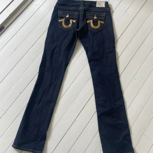 True Religion Jeans - Så snygga True Religion jeans med guldiga paljetter på fickorna! Bootcut men inte super vida. Storlek 28. Ok att köpa direkt! (ni kan även handla hos oss på karlaplans loppis den 2 och 9 augusti!)