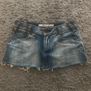 Blå jeanskjol från Only med fransig kant - Säljer en blå jeanskjol från Only med slitna detaljer och fransig rå kant nertill. Kjolen har klassiska fickor fram och bak, bälteshällor och knappstängning. Perfekt för dig som gillar en avslappnad och cool stil.