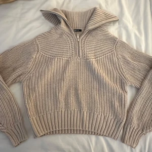 Beige stickad half zip-tröja från Gina Tricot - Säljer en chunky beige stickad tröja från Gina Tricot med half zip och hög krage. Tröjan har breda ribbade muddar och lång ärm, perfekt för lager på lager. Mysig att bära under kyliga dagar. Mycket bra skick, sällan använd. (FRAKT INGÅR EJ)
