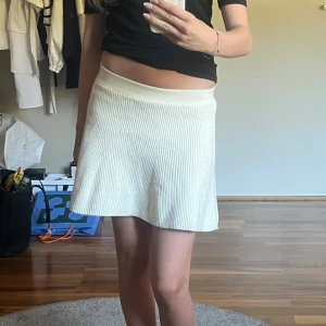 Ribbad kjol från Zara - Superfin ribbad vit/krämfärgad kjol från Zara med stretchig midja och lätt utsvängd passform. Kjolen är stickad och har en mjuk känsla, perfekt till sommaren eller våren. Storlek 152 men sitter som en XS. Har tyvärr aldrig kommit till användning. Säljer även en exakt likadan i svart.