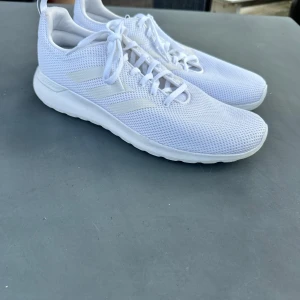 Vita Adidas sneakers - Fräscha helvita Adidas sneakers med de klassiska tre ränder på sidan. Luftiga nätskor som passar för idrotten eller andra aktiviteter. 