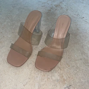 Transparenta sandaler med klack från Zara - Snygga sandaler från Zara med transparenta remmar och fyrkantig tå. Klacken är genomskinlig och ger en modern vibe. Sulan är beige och remmarna i syntetmaterial. Perfekta för dig som gillar trendiga och stilrena skor.