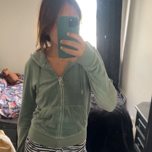 Juicy couture tröja - Juicy couture tröja. Mjuk grön hoodie i velour med dragkedja framtill och huva med snörning. Jackan har två fickor och ribbade muddar vid ärmslut och nederkant. .
