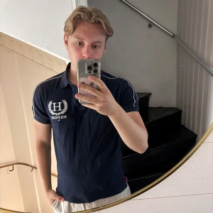 Marinblå pikétröja Tommy Hilfiger M - Snygg marinblå pikétröja från Tommy Hilfiger i slim fit-modell. Tröjan har vit piping längs axlarna, broderad logga och krage. Perfekt för en clean och sportig stil. Materialet är mjuk bomull som andas bra.