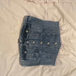 Jeans topp  - Snygg blå jeans topp  med fransig kant och silverfärgade knappar framtill. 