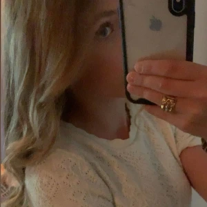 Krämvit stickad topp med spetsdetaljer - Söt krämvit stickad t shirt med kort ärm och fina spetsdetaljer. Perfekt för dig som gillar en romantisk och fräsch stil. Blusen har rund halsringning och ett diskret hålmönster som ger en extra touch.