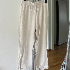Beiga linnebyxor med resårmidja - Säljer ett par beiga linnebyxor i linneblandning  med avslappnad passform och elastisk midja. Byxorna är raka i modellen och har en naturlig, lite grov struktur i tyget. Perfekta för varma dagar och en chill stil.