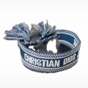 Christian Dior J'adior armband - Snygga Christian Dior J'adior armband i tyg med broderad logga. Finns i både blått och svart med vita detaljer och tofsar i ändarna. Justerbar passform med knytning, perfekt för att ge din outfit en lyxig touch.