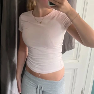 Ljusrosa t-shirt - Säljer en ljusrosa, tight och basic t-shirt med korta ärmar och rund halsringning. T-shirten är enkel och stilren, perfekt att matcha med jeans eller mjukisbyxor. Materialet känns mjukt och följsamt mot kroppen💕