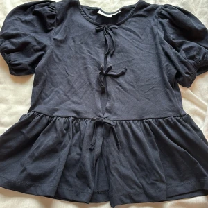 Marin blå blus med puffärm och knyt från Gina tricot - Supersöt marin blå blus med puffiga korta ärmar och tre knyt framtill. Blusen har en volangkant nedtill som ger en flowy känsla. Perfekt för dig som gillar en feminin och trendig look. Tillverkad i mjuk bomull för extra komfort. Den har aldrig blivit använd men lappen är av från tröjan tyvärr 