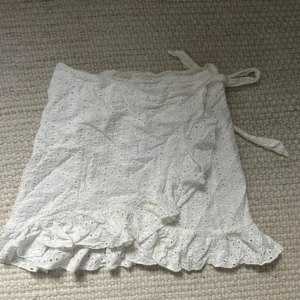 Vit omlottkjol med volang  - Supersöt vit kort omlottkjol från SHEIN i broderad bomull med volangkant och knytband i midjan (första bilden lånad!) ❣️❣️❣️