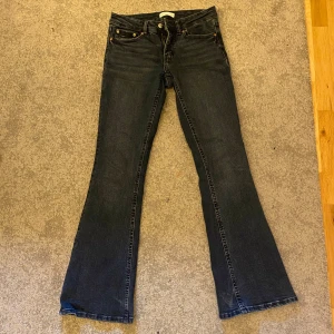 Mörkblå bootcut jeans - Snygga mörkblå jeans med klassisk bootcut-passform. Jeansen har fem fickor, gylf med dragkedja och knapp samt subtila slitningar för en cool look. Perfekta för dig som gillar en tidlös stil med lite extra vidd nertill.