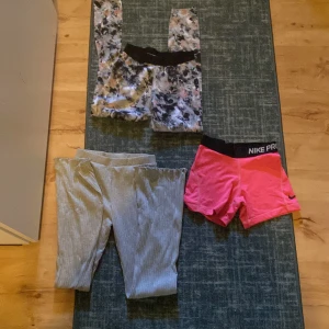 Nike Pro rosa träningsshorts, mjukbyckor Kappahl och träningsbyxor SOC - Nike Pro shorts i stark rosa med svart resår och logga storlek M. Sitter tight och är perfekta för träning eller sport. Materialet är mjukt och stretchigt syntet som andas bra. Snygg och sportig, kostar 30.                               Gråa mjukis byxor storlek 146. Dom har grå resår i midjan, skönt matrial, kostar 50.          Blommiga träningsbyxor storlek 146-152. Fina och sköna har också svart resår i midjan. Behagliga och mjuka, kostar 20.             ALTING IHOP KOSTAR 80.