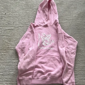 Rosa hoodie Internationella Engelska Skolan - Säljer en ljusrosa hoodie från Internationella Engelska Skolan med vit tryckt logga och motiv framtill. Tröjan har huva, magficka och långa ärmar. Perfekt för dig som gillar en chill och enkel stil. 