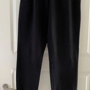 Svarta mjukisbyxor från Frank Dandy - Svarta mjukisbyxor från Frank Dandy med resår i midjan och mjukt, fleeceliknande material på insidan. Perfekta för chill eller när du vill vara bekväm. Klassisk rak passform och stilren look.