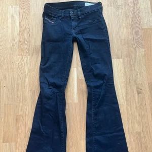 Mörkblå bootcut jeans från Diesel - Snygga mörkblå jeans från Diesel med klassisk femficksdesign och bootcut-ben. Jeansen har stretchigt material för extra komfort och en diskret logga på myntfickan. Perfekta för dig som gillar en retroinspirerad look med utsvängda ben.