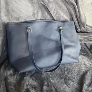 Mörkblå axelväska med dragkedja - Snygg mörkblå axelväska.Väskan har ett rymligt huvudfack, innerficka med dragkedja och ett fack till. Bra skick, knappt använd. Mått 42x26 30kr+frakt