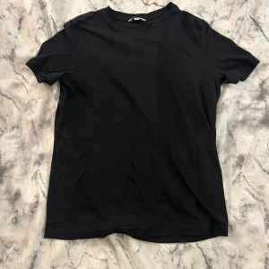 Svart basic t-shirt i bomull - Enkel svart t-shirt med rund hals och korta ärmar. Tillverkad i mjuk bomull som känns skön mot huden. 