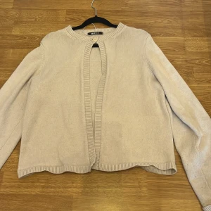 Beige/vit  stickad kofta från Gina Tricot - En stilren beige/vit stickad kofta från Gina Tricot i storlek L. Koftan har rund halsringning, ribbade kanter och stängs med en enkel knapp upptill. passar till allt i garderoben.