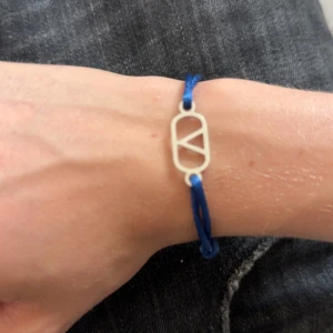 Valentino liknande armband  - Snyggt armband med blå snöre och en cool silverfärgad detalj i mitten med geometriskt mönster. Perfekt för dig som gillar minimalistisk stil och vill ha något som sticker ut lite extra på handleden.