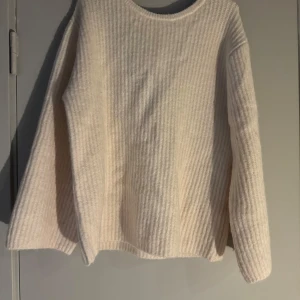 Creamvit stickad tröja med rosett och öppen rygg  - Supermysig oversized creamvit stickad tröja med ribbad struktur och lång ärm. Baksidan har en djup v-ringning med en vit rosett som detalj. Perfekt för dig som gillar en enkel men ändå söt look. 🥰🫶🏻helt ny! Stor i storleken, så mer som en M 