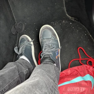 Mörkblå sneakers med broderad stjärna - Säljer ett par mörkblå sneakers med vit sula och grå snörning. Skorna har en broderad stjärna i orange och blå på sidan samt detaljer i mocka vid tån. Perfekt för dig som gillar en clean look med lite extra edge.