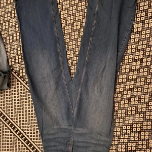 Levis 511 blå jeans bootcut - Säljer ett par klassiska Levis 511 jeans i blå tvätt med bootcut passform. Jeansen har raka ben och subtila slitningar för en cool look. Materialet är mjukt jeans och de har detaljerade sömmar längs benen. Perfekta för dig som gillar tidlös stil.
